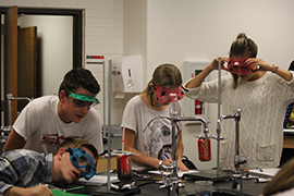 SUCCESS students doing experiements with soda cans in the science room with safety goggles on.