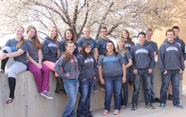 SUCCESS Academy's student government students pose in front of trees with spring buds